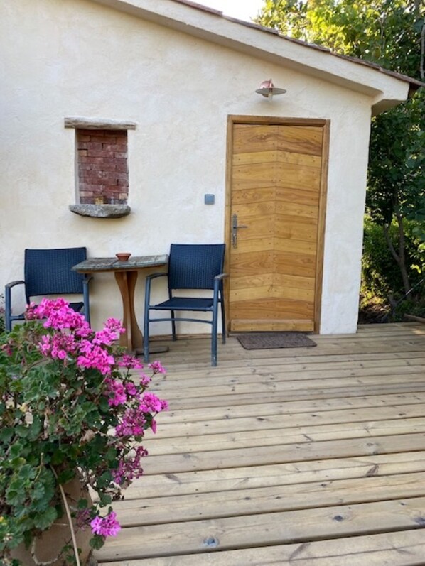Un edificio pequeño con una puerta de madera, una ventana y una mesa con dos sillas.