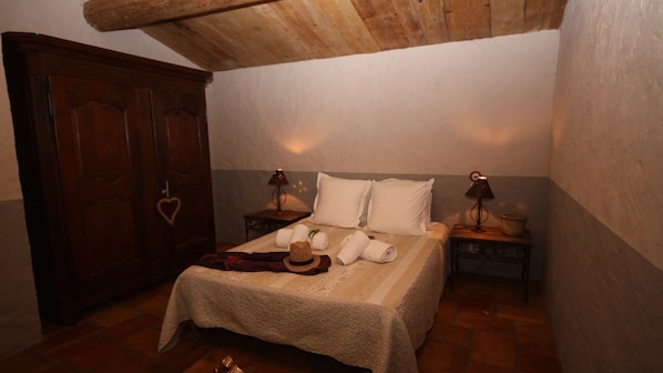 A bedroom with a wooden wardrobe, a bed with white linens, two bedside lamps, and a rustic hat on the bed. - Auberge U Sirenu (Sartene)