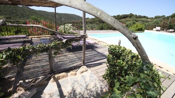 A wooden deck with lounge chairs, a swimming pool, and a view of a mountainous landscape. - Auberge U Sirenu (Sartene)
