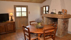 A cozy dining area with a wooden table and chairs, a television on a cabinet, and a fireplace with decorative items. - Auberge U Sirenu (Sartene)