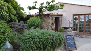 A rustic building with a stone facade, a wooden door, and a signboard with a menu. - Auberge U Sirenu (Sartene)