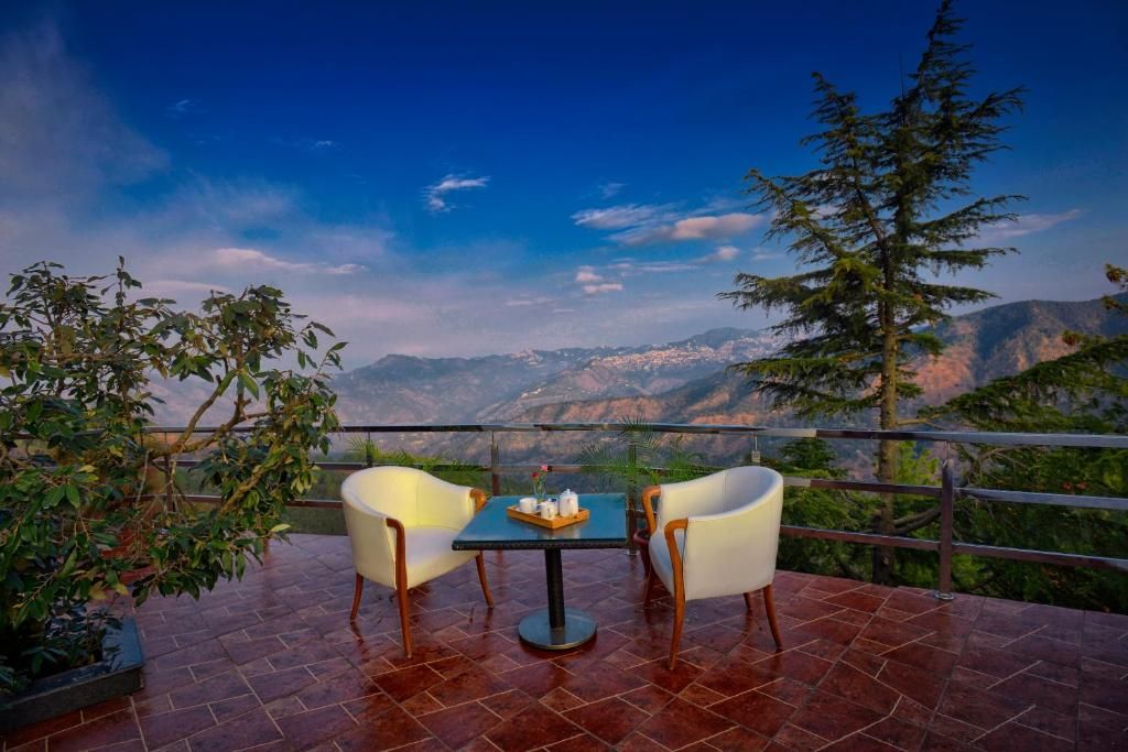Un espace extérieur aménagé avec une table et des chaises, offrant une vue sur un paysage montagneux.
