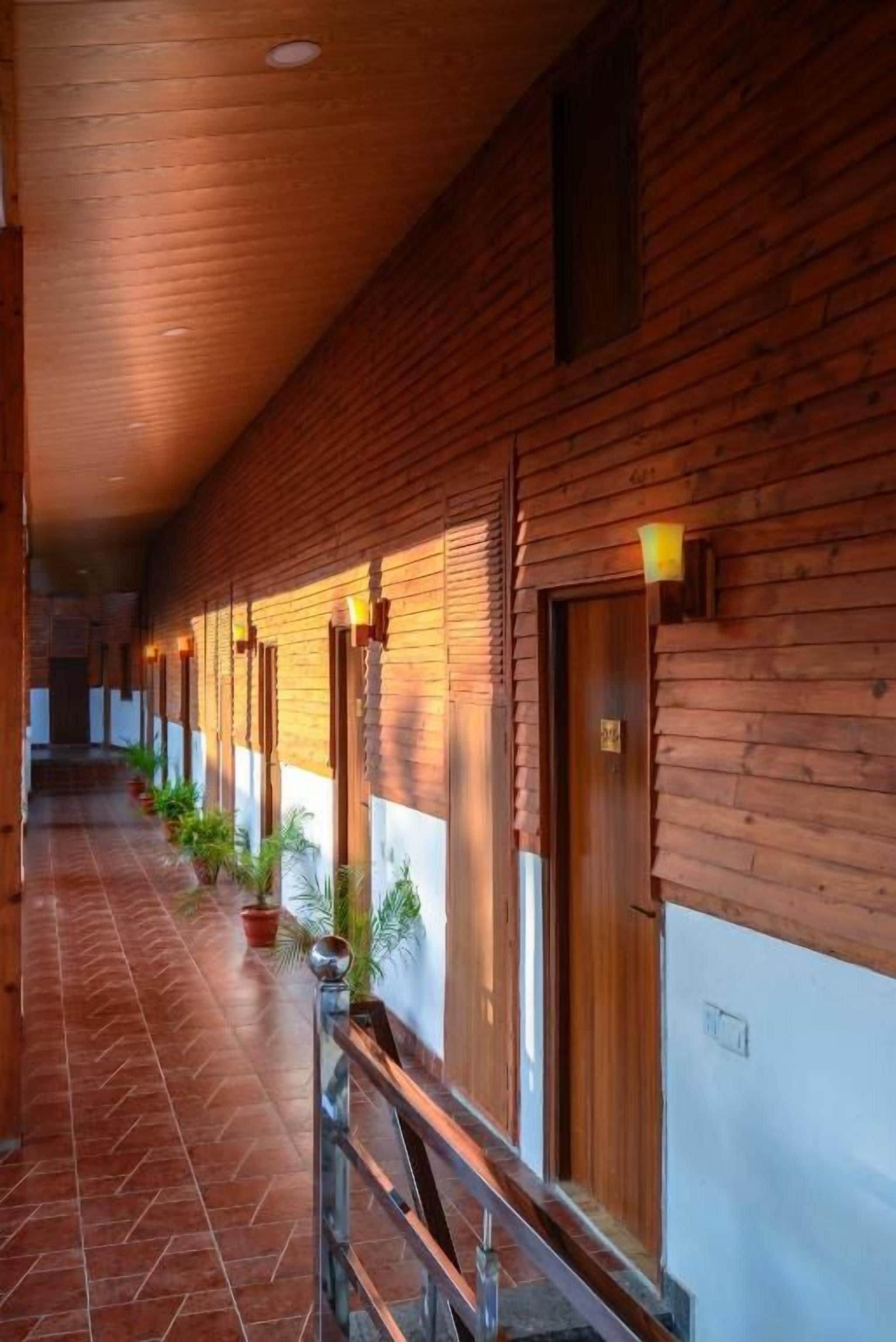 A corridor with wooden paneling, potted plants, and a tiled floor.