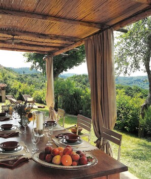 An outdoor dining area with a table set for a meal, surrounded by lush greenery and hills in the background. - Lone standing Villa, 180 m²(1960 ft²) pool, sea view, eco friendly, EV wall box (Camaiore)
