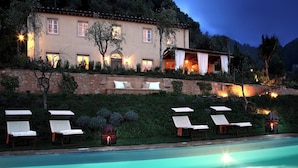 Zona junto a la piscina con sillones de descanso y una alberca.