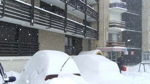 Un edificio de varios pisos y balcones, cubierto de nieve.
