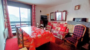 Una habitación con cama, sofá, televisor y ventana con cortinas.