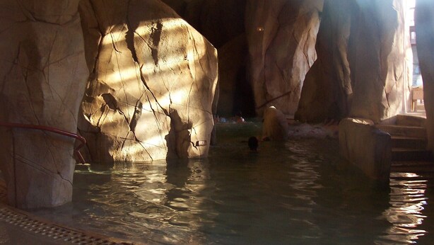 Una estructura similar a una cueva con agua y una persona dentro.
