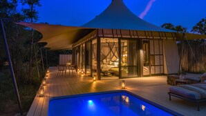 A cozy, well-lit outdoor area with a pool, comfortable seating, and a large canopy providing shade. - Saseka Tented Camp (Hoedspruit)