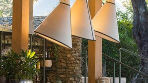 A wooden deck with stone walls, hanging lamps, and outdoor seating. - Saseka Tented Camp (Hoedspruit)