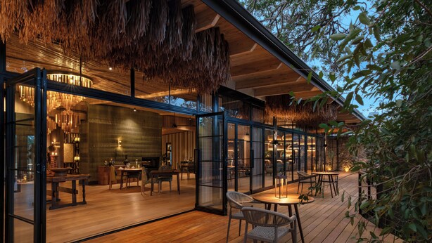An interior with wooden flooring, glass partitions, and a dining area with tables and chairs. - Saseka Tented Camp (Hoedspruit)