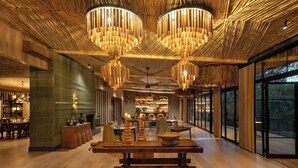A spacious interior with a central wooden table, hanging wooden chandeliers, and large windows offering views. - Saseka Tented Camp (Hoedspruit)