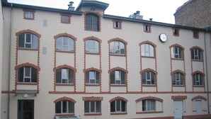 Um edifício com várias andares e fachada simétrica, com uma série de janelas em arco e um relógio central.