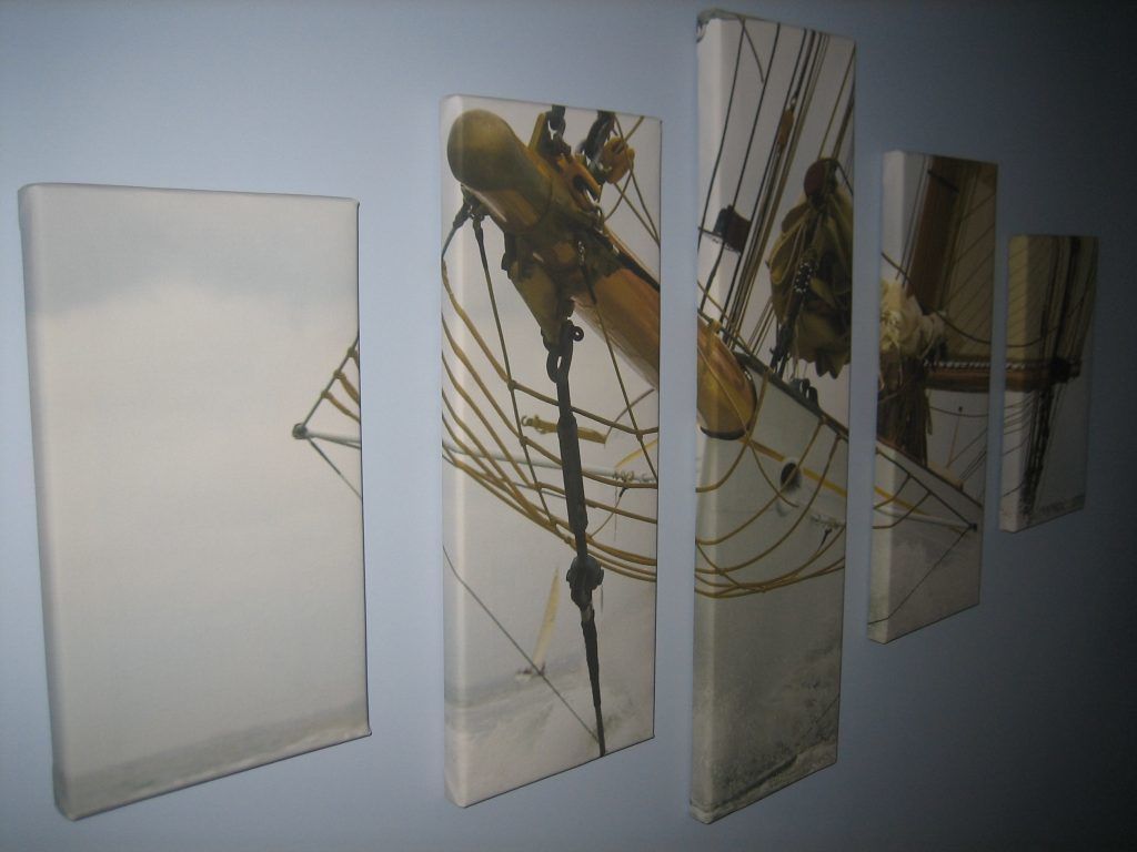 A wall with four framed artworks depicting mechanical or industrial scenes.