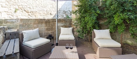An outdoor patio with wicker furniture, including two sofas and a table, under a large umbrella.