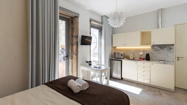Ein modernes Hotelzimmer mit Bett, Schreibtisch und Küchenzeile.