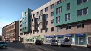 Ein mehrgeschossiges Gebäude mit modernem architektonischen Design, das Backsteinelemente und grüne Fassadenelemente kombiniert.