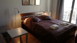 Ein Hotelzimmer mit Bett, Nachttisch, Lampe und Blick ins Freie.