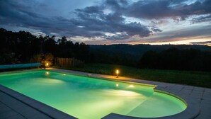 Una piscina rectangular con borde curvo, rodeada por una solana pavimentada.