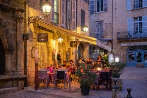 An outdoor café with tables and chairs, a street view, and a building with a sign. - Restored farmhouse from the 17th century with swimming pool and beautiful views (Saint-Amand-De-Coly)