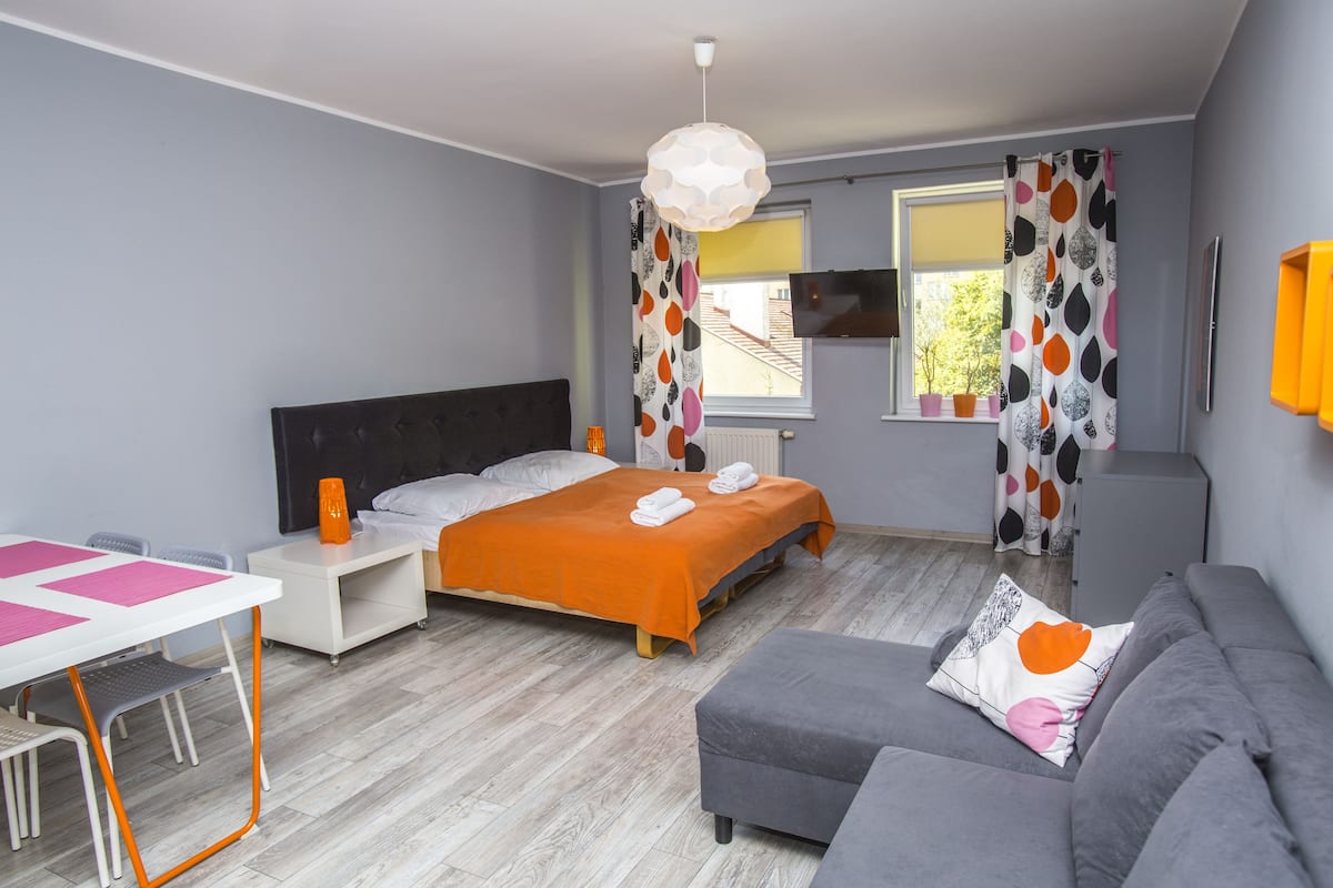 Ein modernes Schlafzimmer mit Bett, Sofa, Schreibtisch und Fernseher.