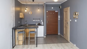 Uma cozinha compacta com um banquinho de bar, um armário de madeira e uma porta de madeira.