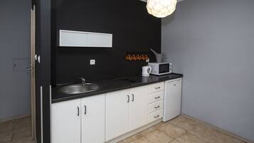 A modern kitchen with white cabinets, a black countertop, a microwave, and a hanging light fixture.