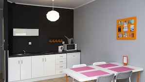 Cozinha compacta com armários brancos, micro-ondas e luminária pendente.