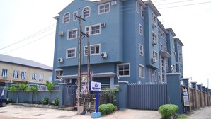 A multi-story building with a blue facade, air conditioning units, and a gated entrance. - DAWN CARRINGTON HOTELS AND SUITES (Lagos)