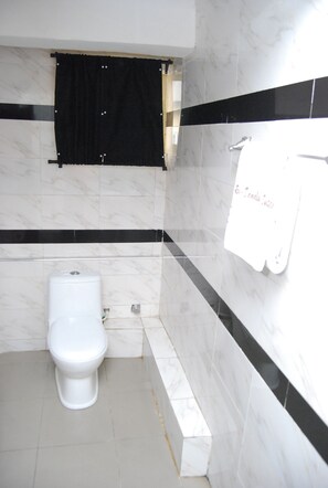 Une salle de bain avec des toilettes, un porte-serviettes et un rideau noir.