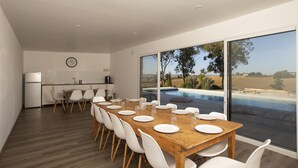 A modern dining area with a wooden table set for six, white chairs, a kitchen in the background, and a large window overlooking a swimming pool and landscape. - A SPIRIT OF FAMILY **** (4 ears) (Faudoas)