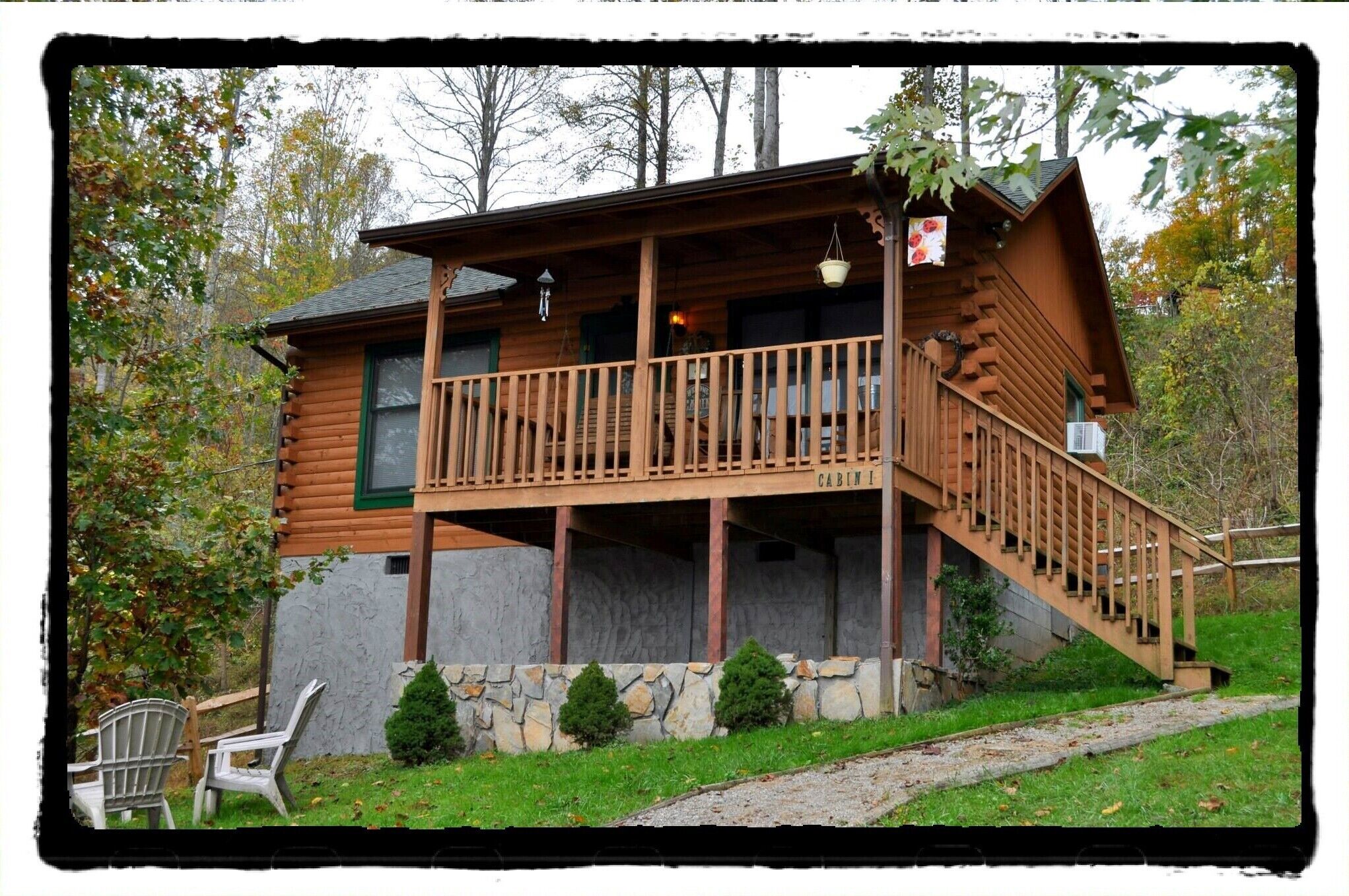 A log cabin with a wooden deck and a stone foundation.