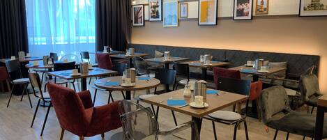 A modern dining area with multiple tables and chairs, some with clear backs and others with cushioned seats.