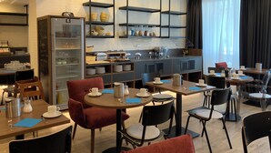 Uma área de refeições moderna com mesas redondas, cadeiras e um balcão de buffet.