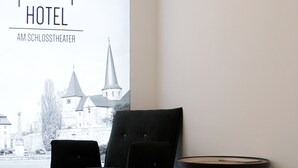 Quarto de hotel com vista para um edifício histórico, uma cadeira preta e uma mesa redonda pequena.