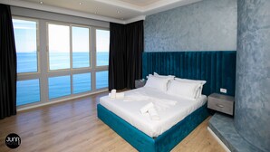 Habitación de hotel moderna con una cama grande, una mesita de noche y vistas al mar.