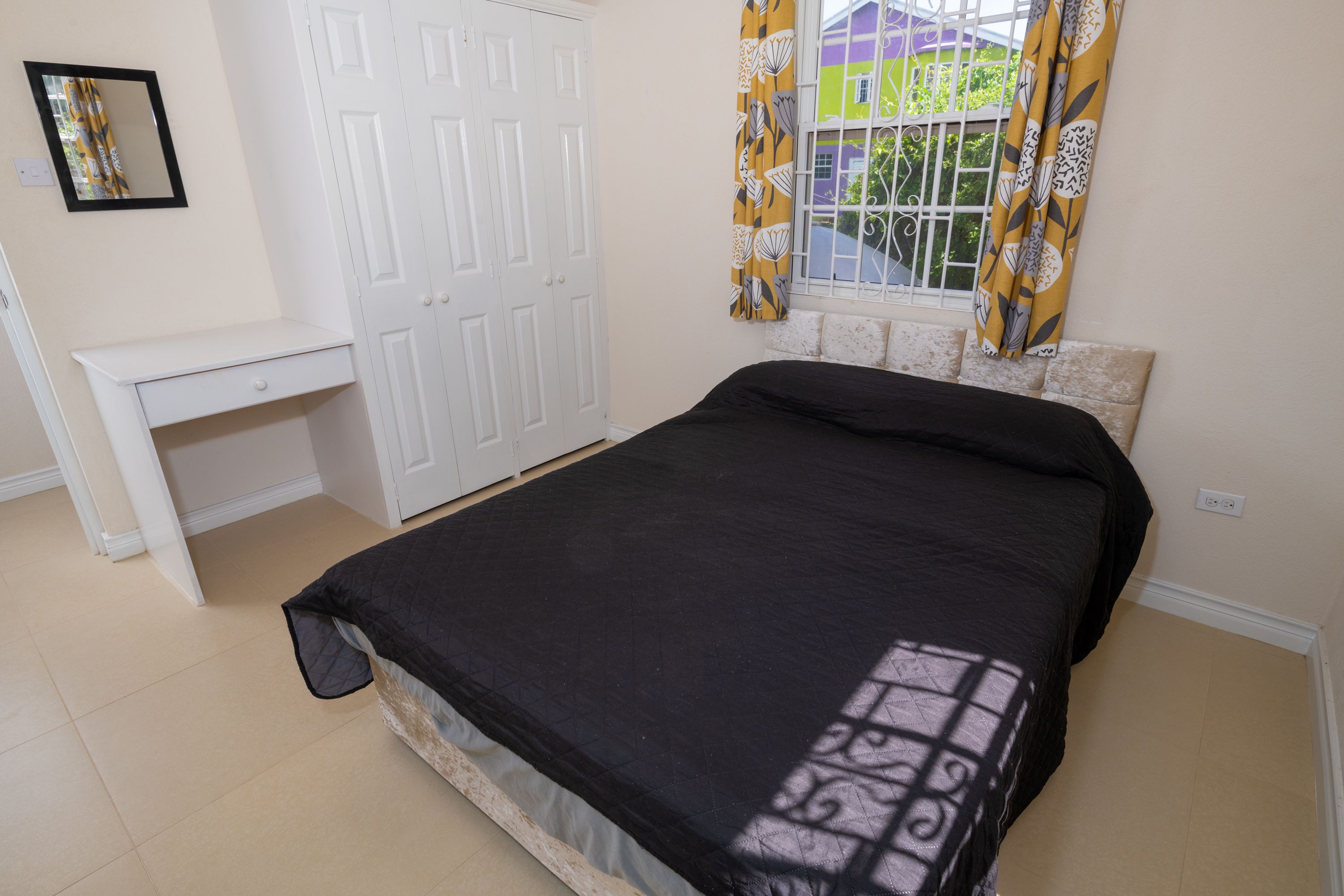 A bedroom with a bed, a desk, and a wardrobe.
