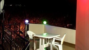 Un balcon avec une table et des chaises, une balustrade et un luminaire rouge.