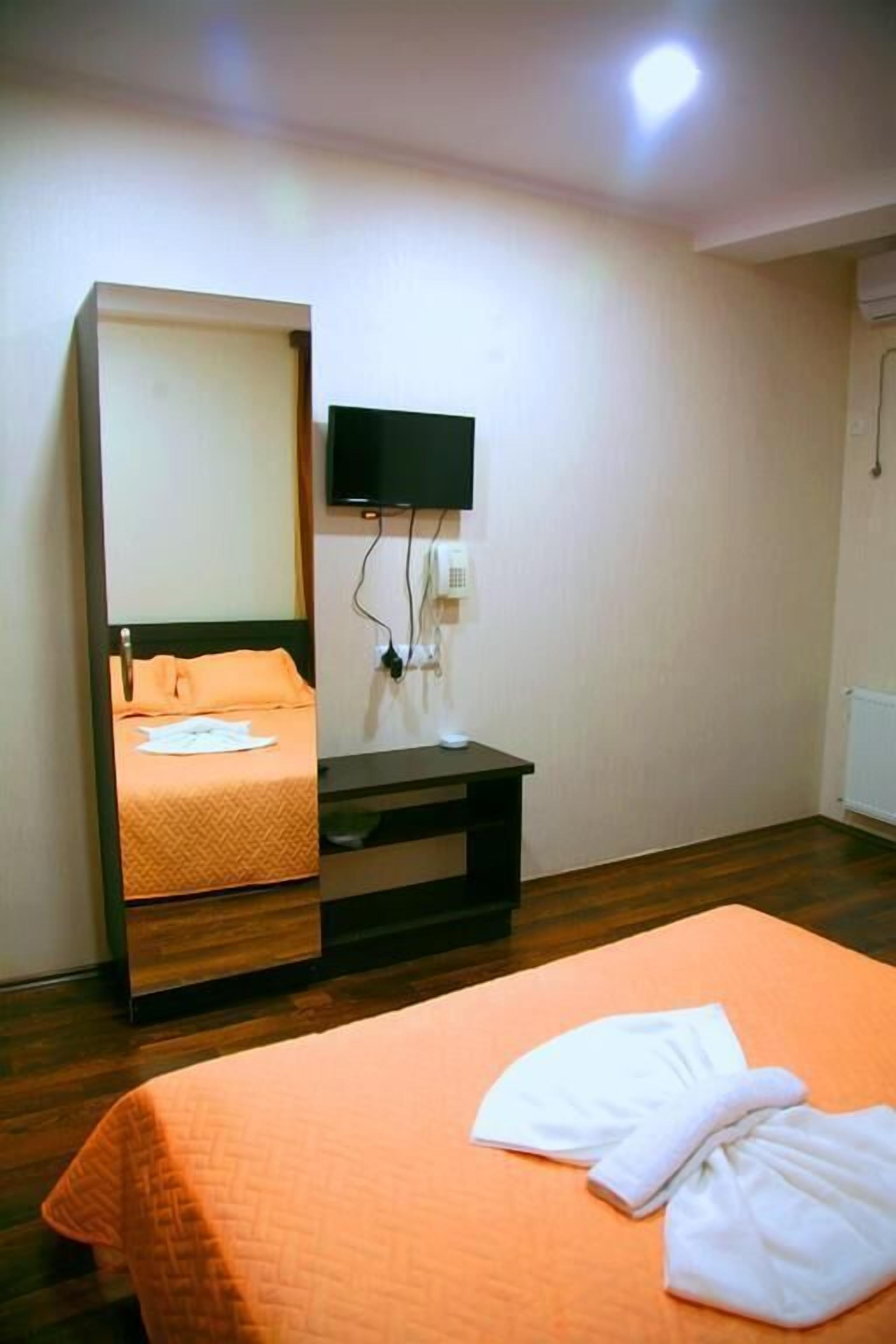 Ein Hotelzimmer mit Bett, Nachttisch, Wandfernseher und Spiegel.