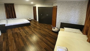 Une chambre d’hôtel avec deux lits, une armoire et une petite table.
