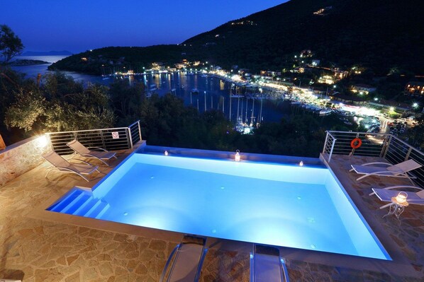 A swimming pool with a view of a marina at night.