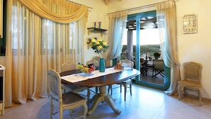 A dining area with a round table, chairs, and a view through a glass door to an outdoor patio. - Ktima Aniforeli Luxury Villas (Lefkada)