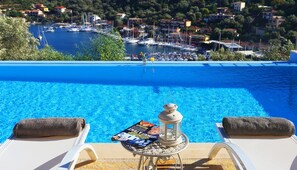 A poolside view with lounge chairs, a magazine, and a lantern.