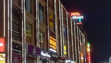 A multi-story building with illuminated signage for various businesses, including a restaurant and a hotel.