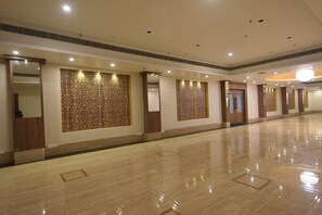 Un pasillo amplio de hotel con suelos de mármol pulido, puertas de madera y paneles decorativos.