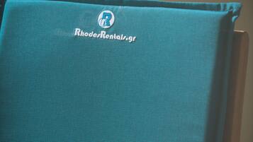 Una silla de tela color aguamarina con un logotipo y el texto "RhodesRentals.gr".