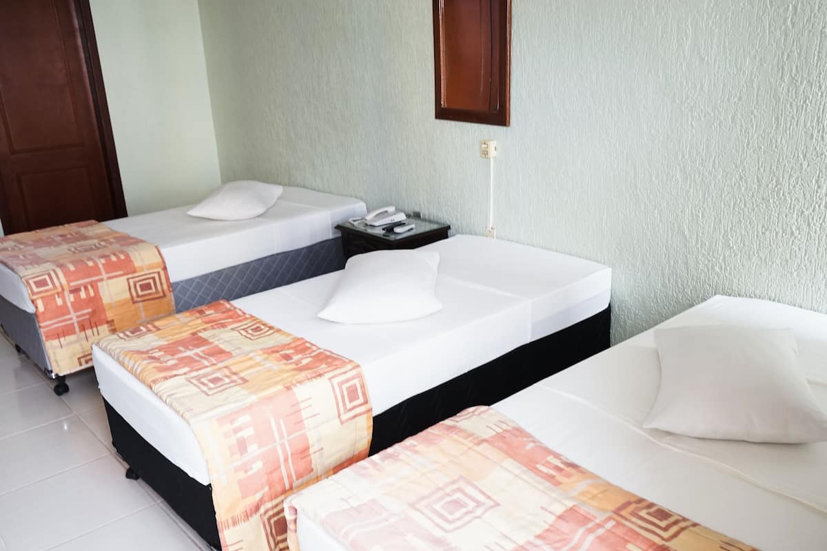 A hotel room with two beds, a nightstand, a telephone, and a wall-mounted light fixture.