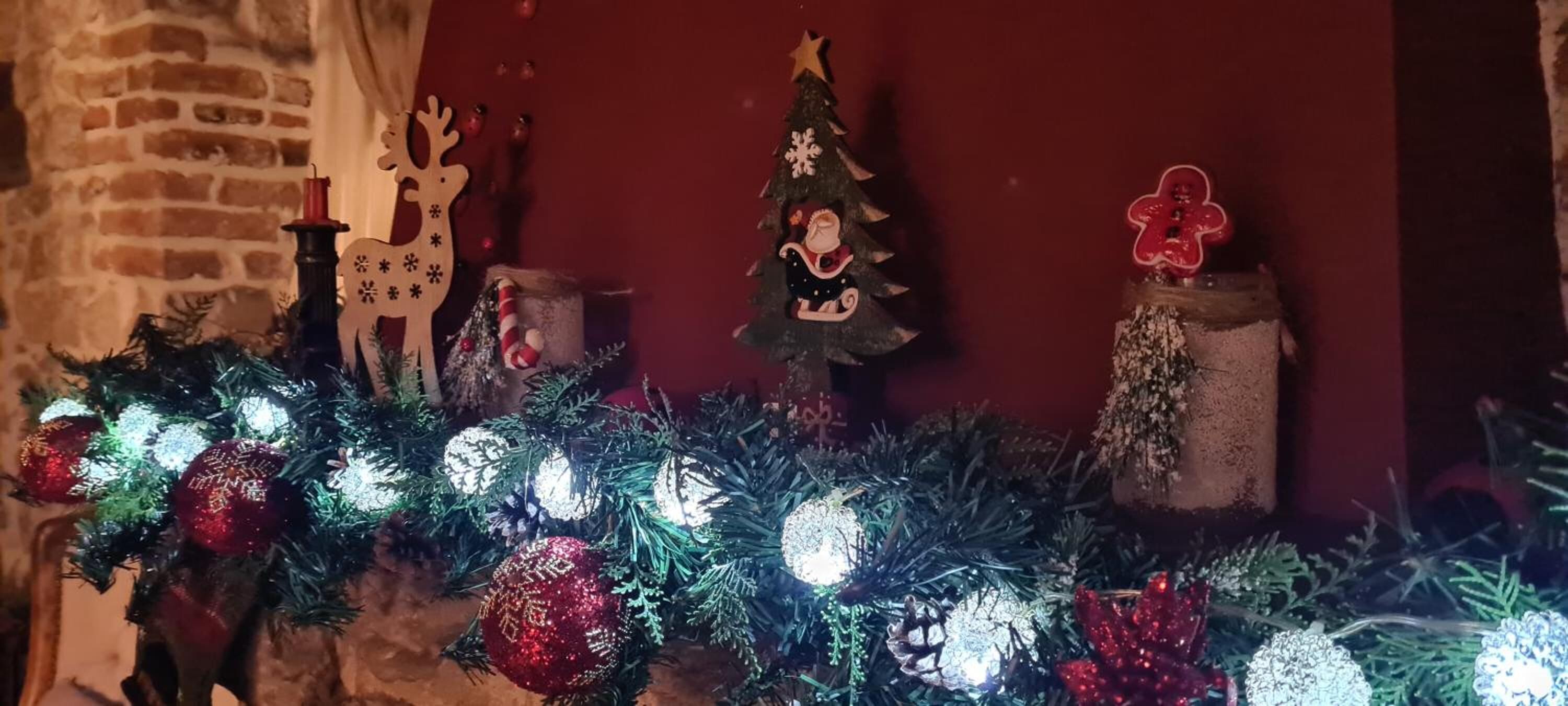 Una repisa decorada con un árbol de Navidad, adornos y una figura de reno.