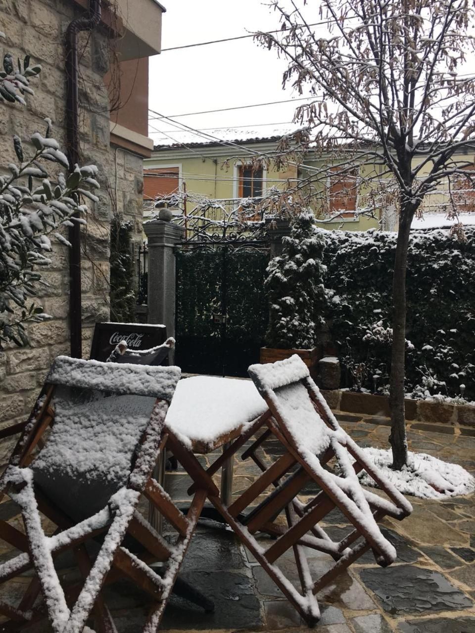 Mobiliario exterior con acumulación de nieve, una pared de piedra y un letrero de Coca-Cola.