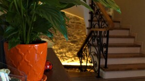A potted plant on a wooden table, a red ladybug, and a staircase with a stone wall and wrought iron railing. - Vila Trebicka (Korçë)